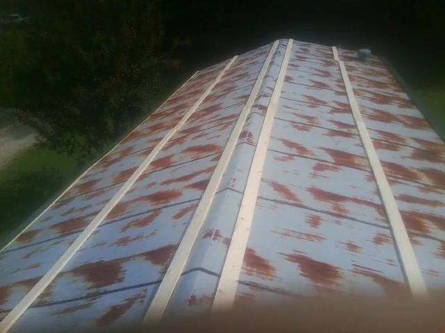 Rusted metal roof panels with new wood purlins before replacement — Storm Damage Roof Repair in Almont by Roofing Brothers