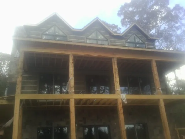 Dormers and porch framing on a large log home under construction — Roof Coating work by our crew in Almont