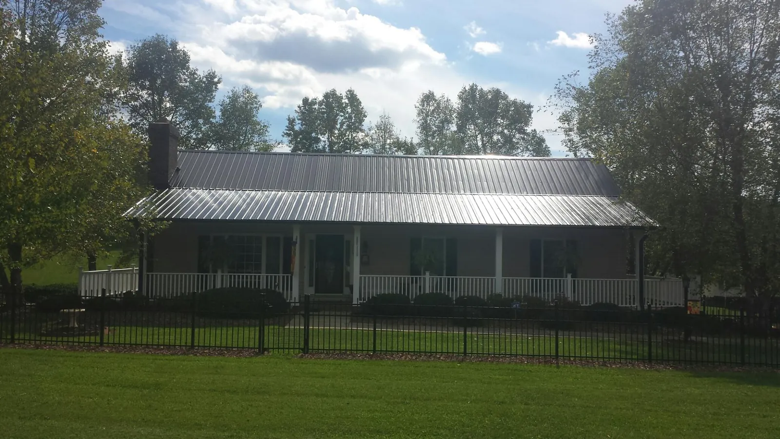 Gray metal roof on a brick ranch with a full width front porch — Gutter Guard Installation work by our crew in Almont