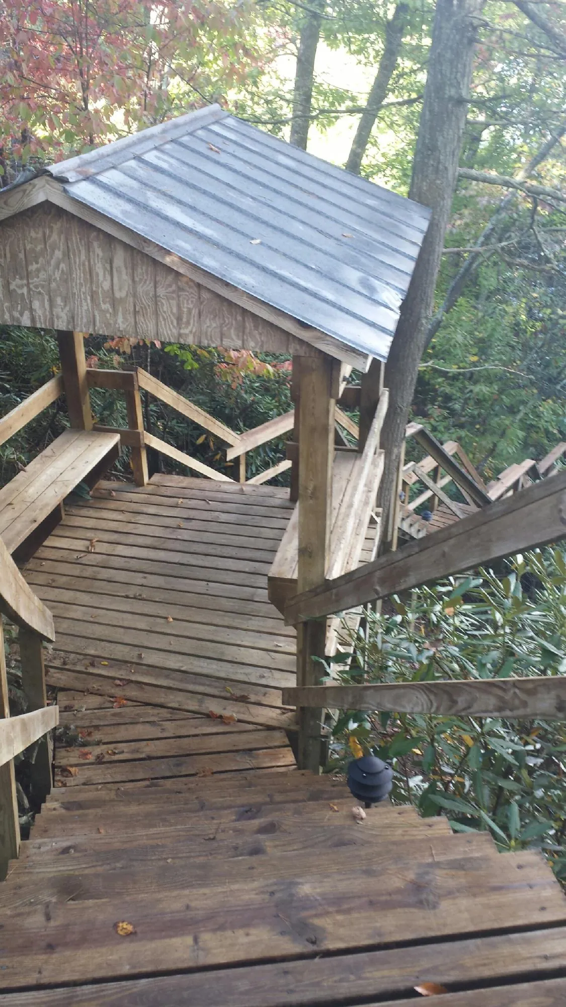 Metal roofed shelter over wooden steps on a wooded walkway — Skylight Repair & Installation work by our crew in Almont