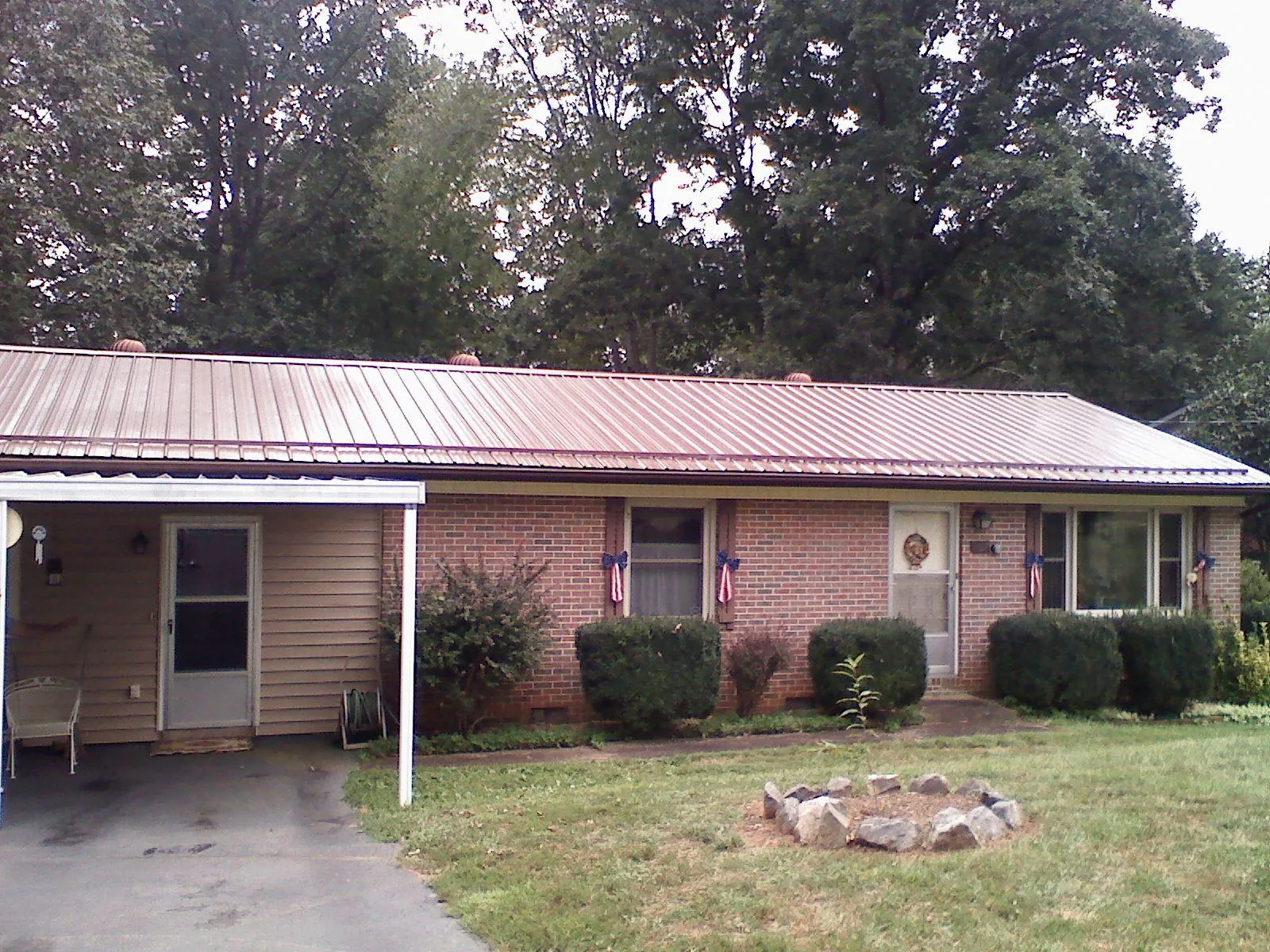 Bronze metal roof and carport on a brick ranch home — Roof Repair work by our crew in Almont
