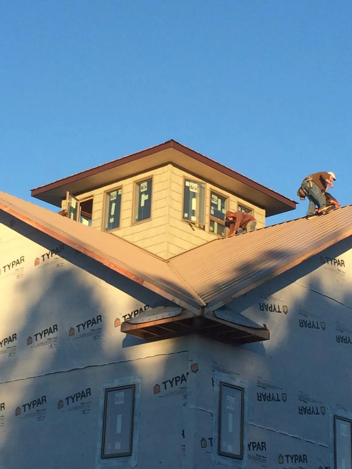 Roofers working around a rooftop cupola on a new metal roof at sunset — Roof Waterproofing in Almont by Roofing Brothers